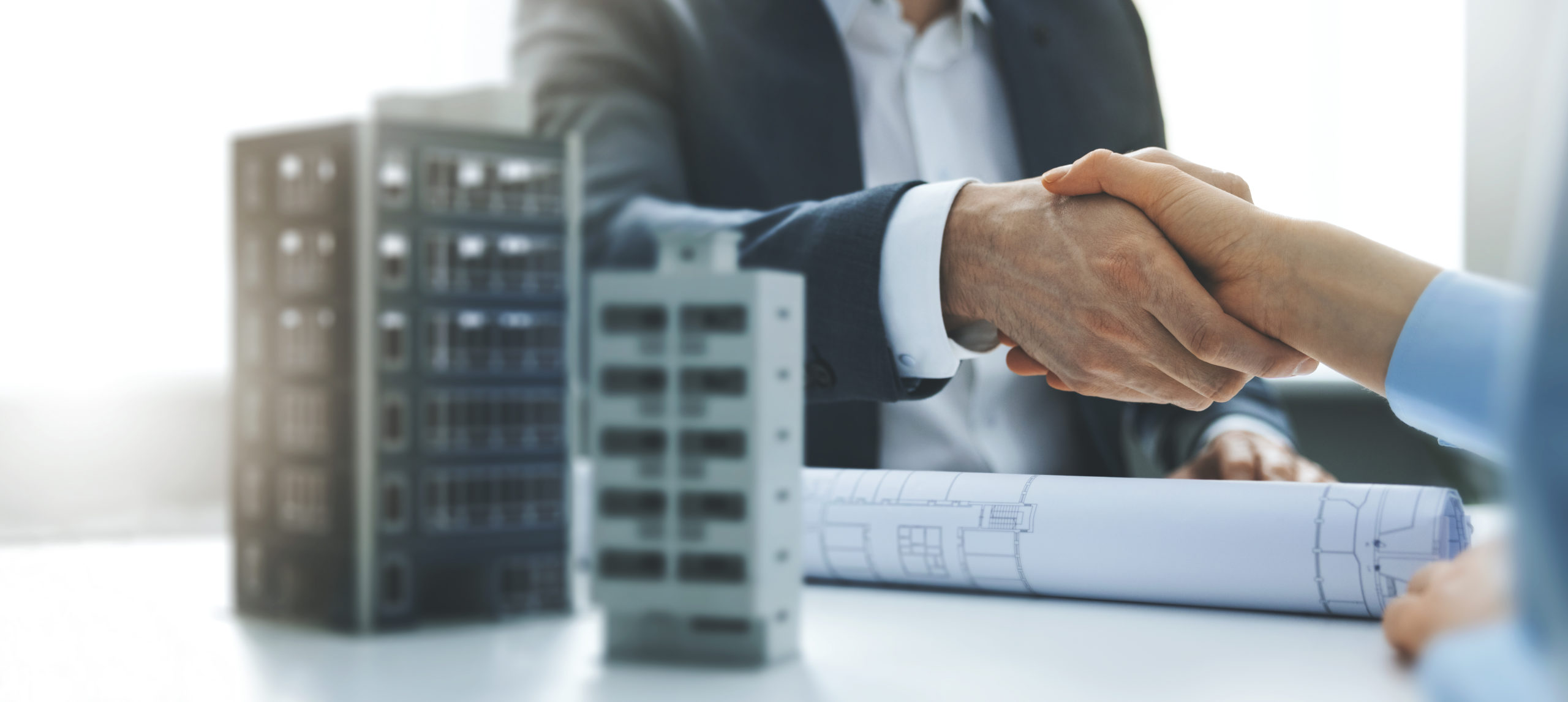 housing development and investment business - businessmen handshake after agreement of apartment building construction. banner copy space